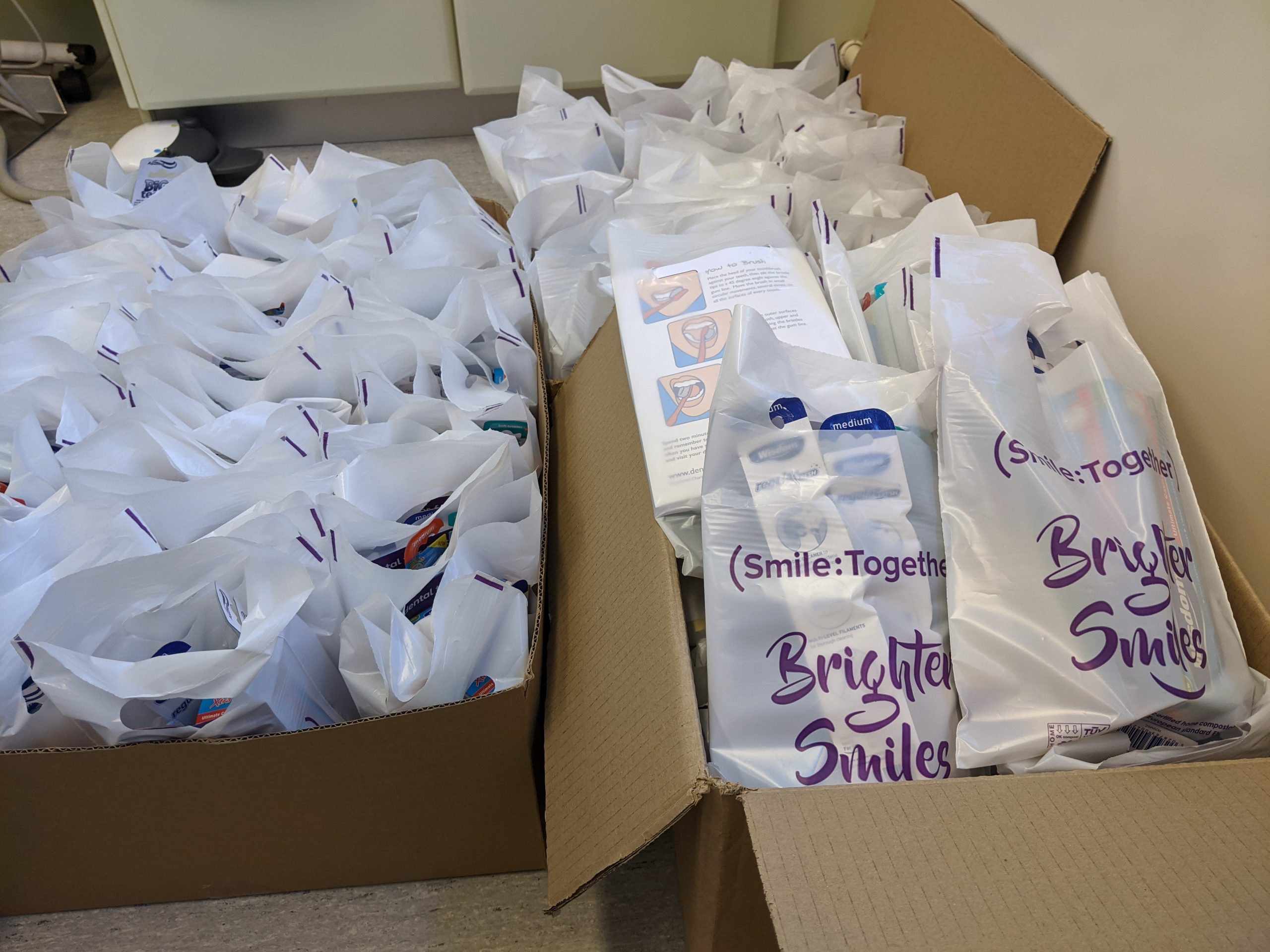 Two boxes full of oral health packs showing Smile Together and Brighter Smiles logos