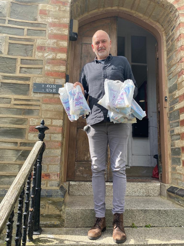 Man holding bags of oral health packs on doorstep