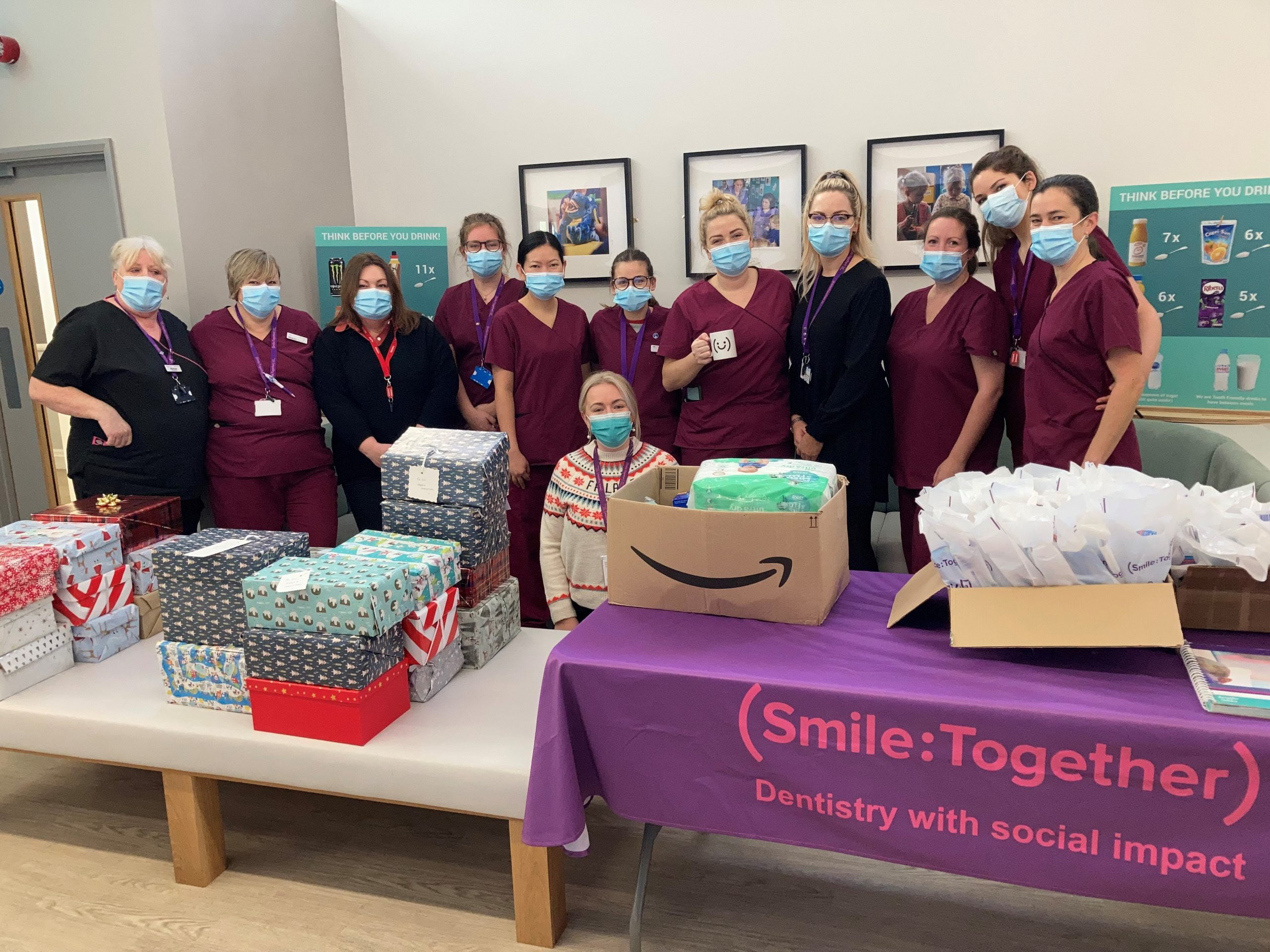 Smile Together dental team masked standing at table with donation boxes and oral health packs