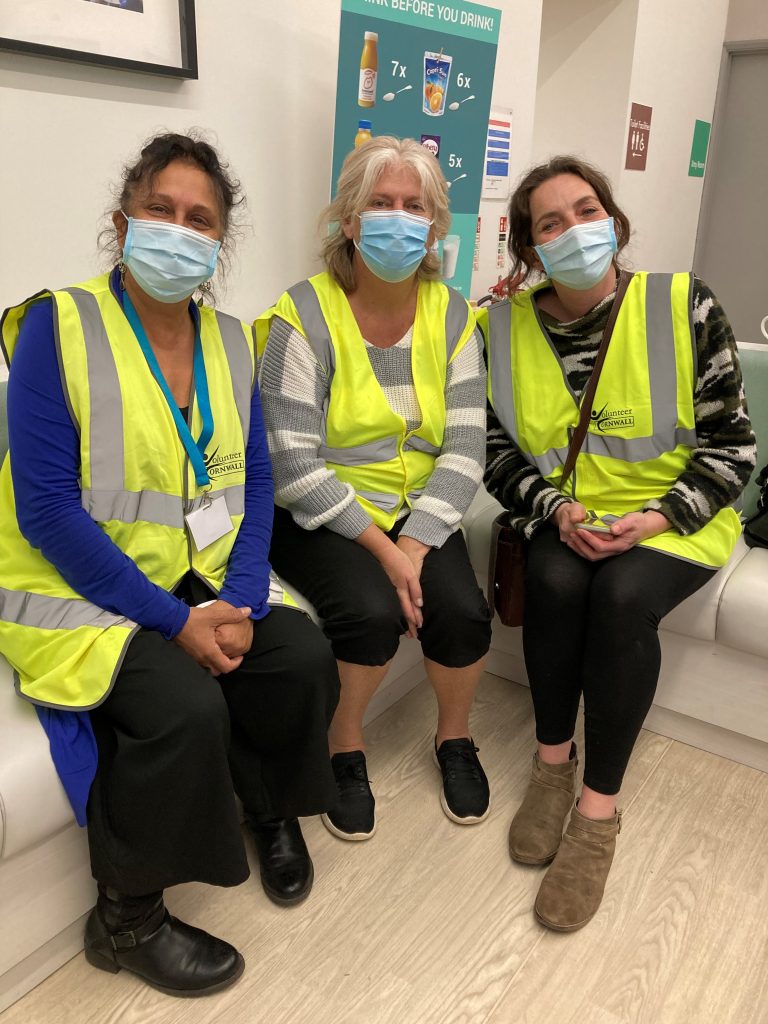 Three people wearing masks and hi-vis sitting in dental waiting area