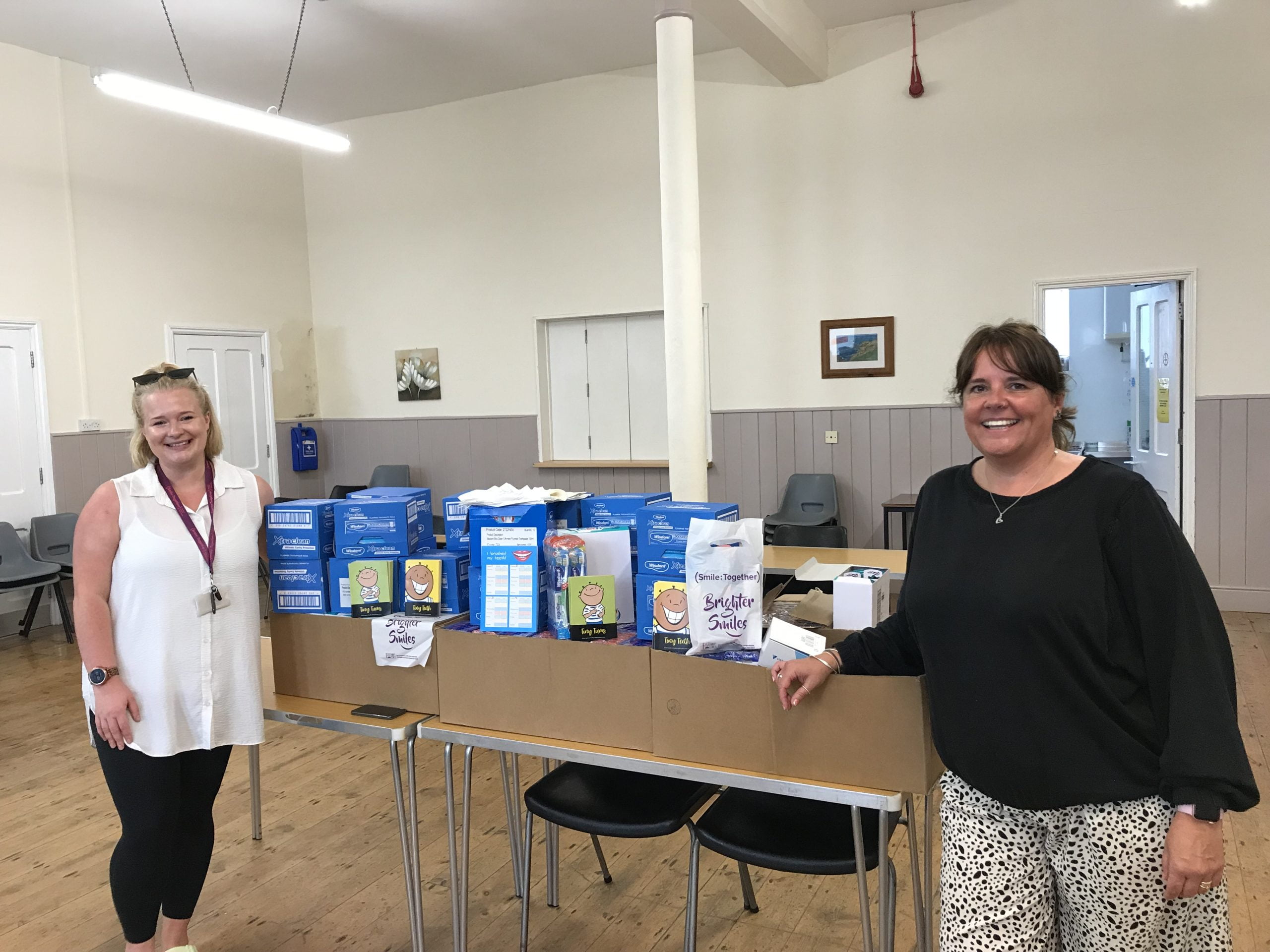 Lucy and Ali stood by three boxes of oral health pack stock