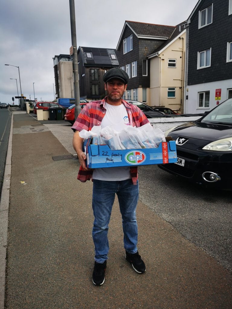 Man holding box of oral heath packs outside