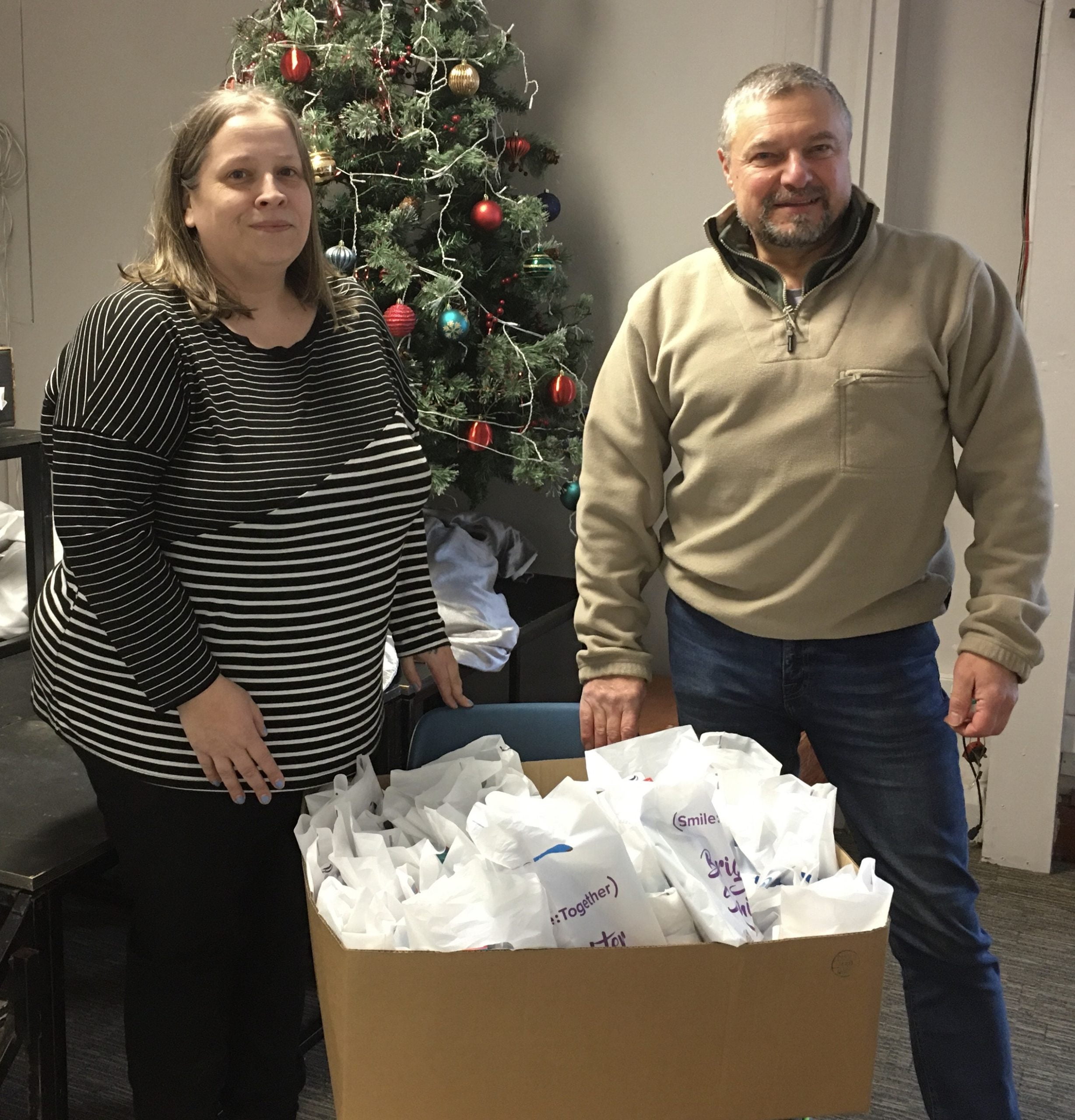 woman and man stood by box of oral health packs with christmas tree in the background