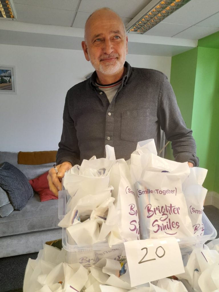 man holding a box of oral health packs and looking to the right