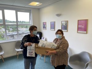 two people stood in waiting area holding a box of oral health packs