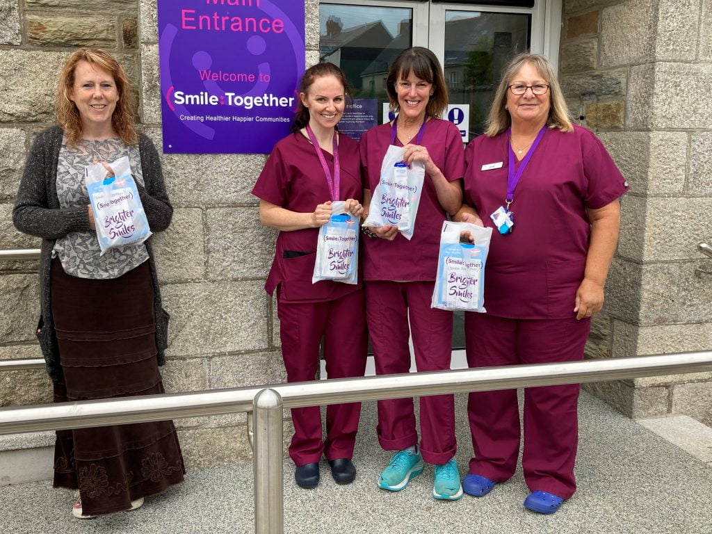 four women holding oral health packs outside main entrance to Smile Together Bodmin