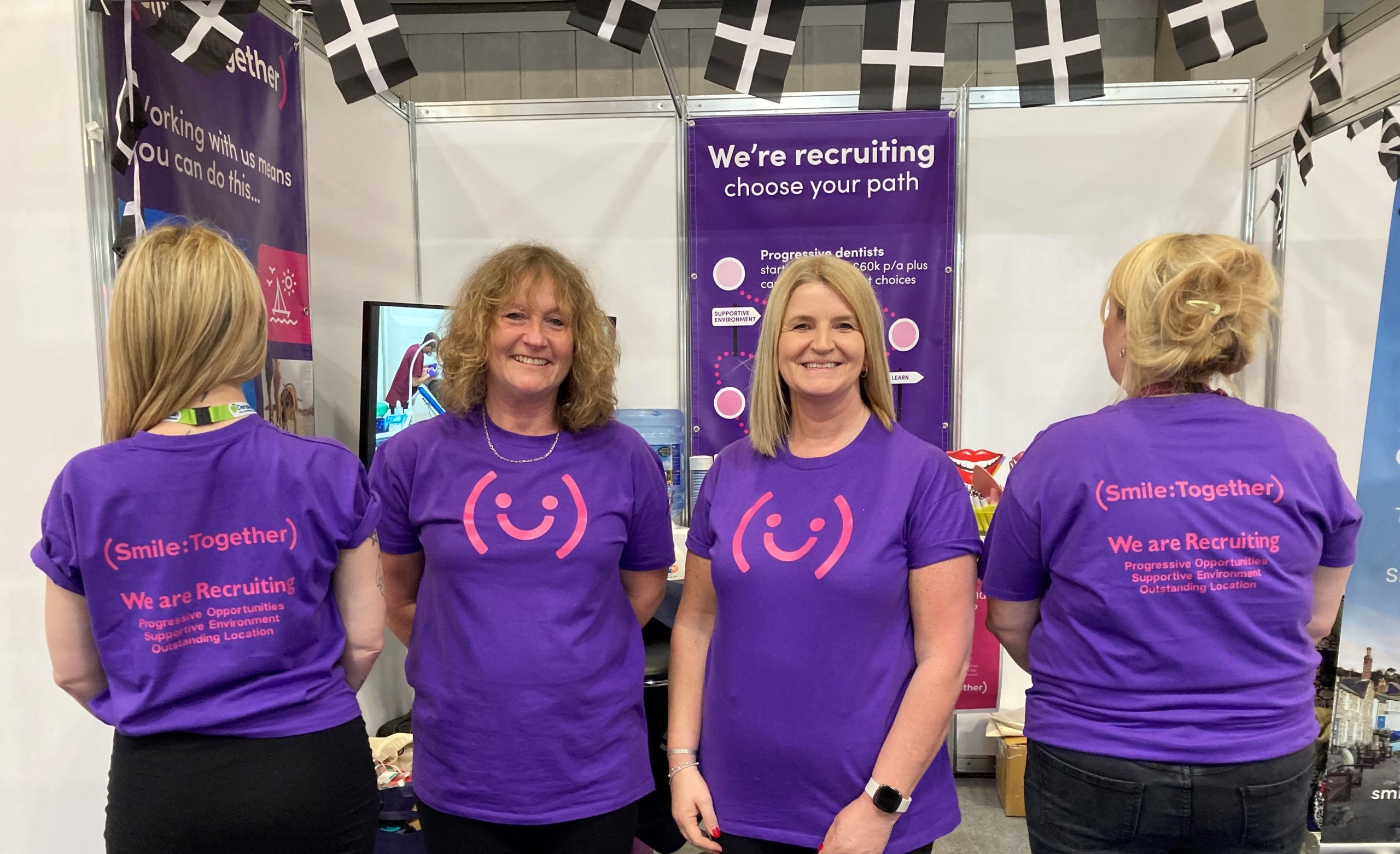 Four people wearing Smile Together purple branded T-shirts