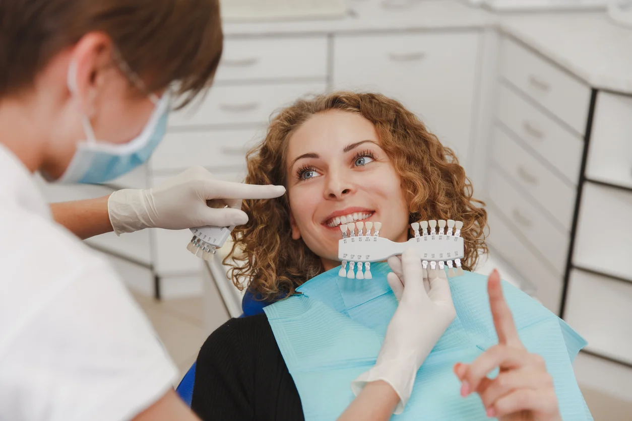 Dentist comparing patient's teeth shade with samples for bleaching treatment